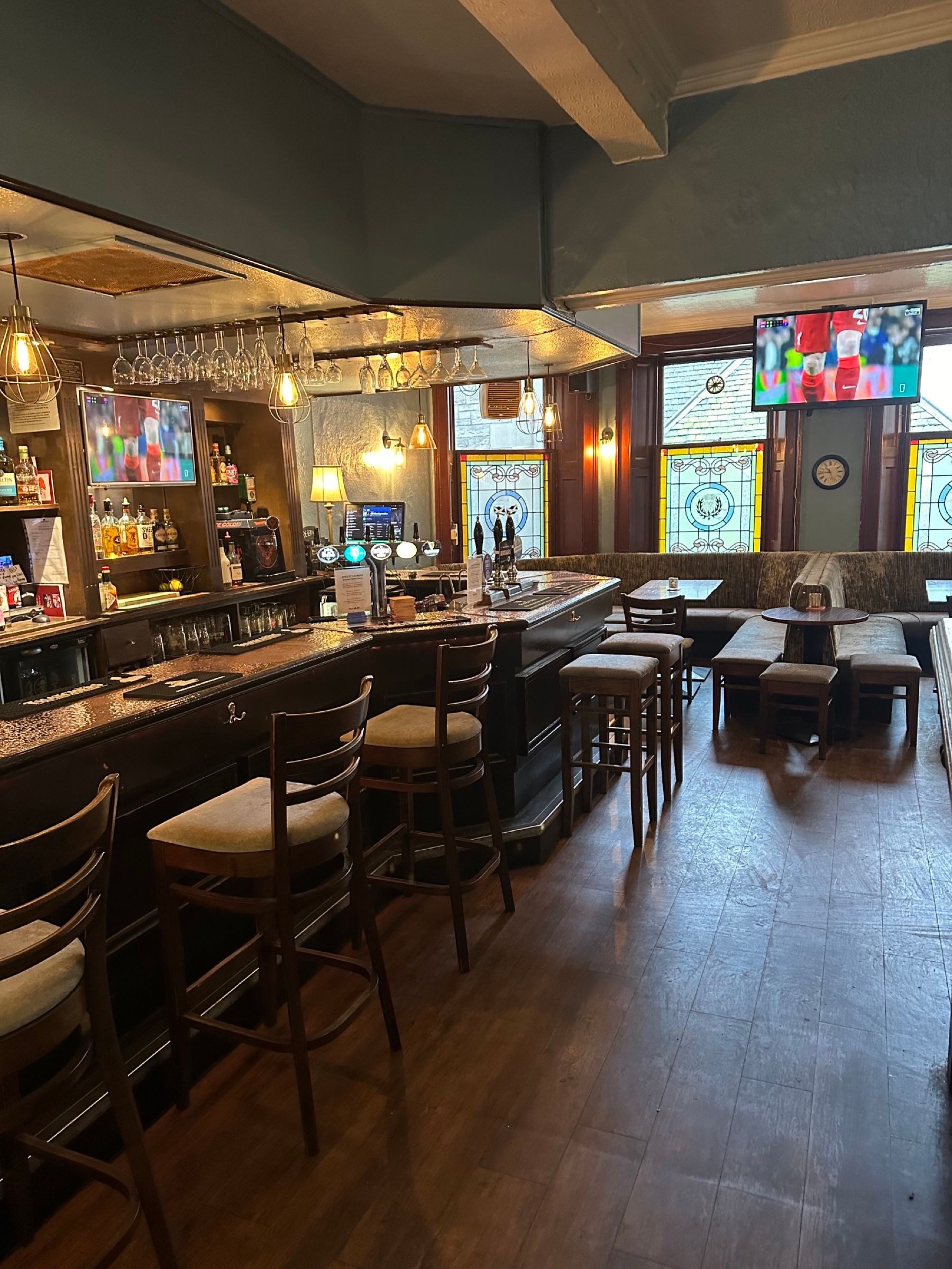The front room, looking along the bar to the stained glass windows, with the football on the screens
