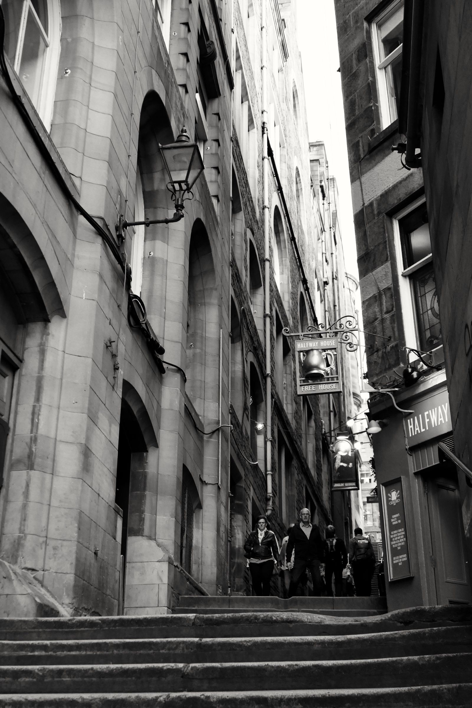 Looking up the close between the tenements, with the pub’s hanging sign on the right