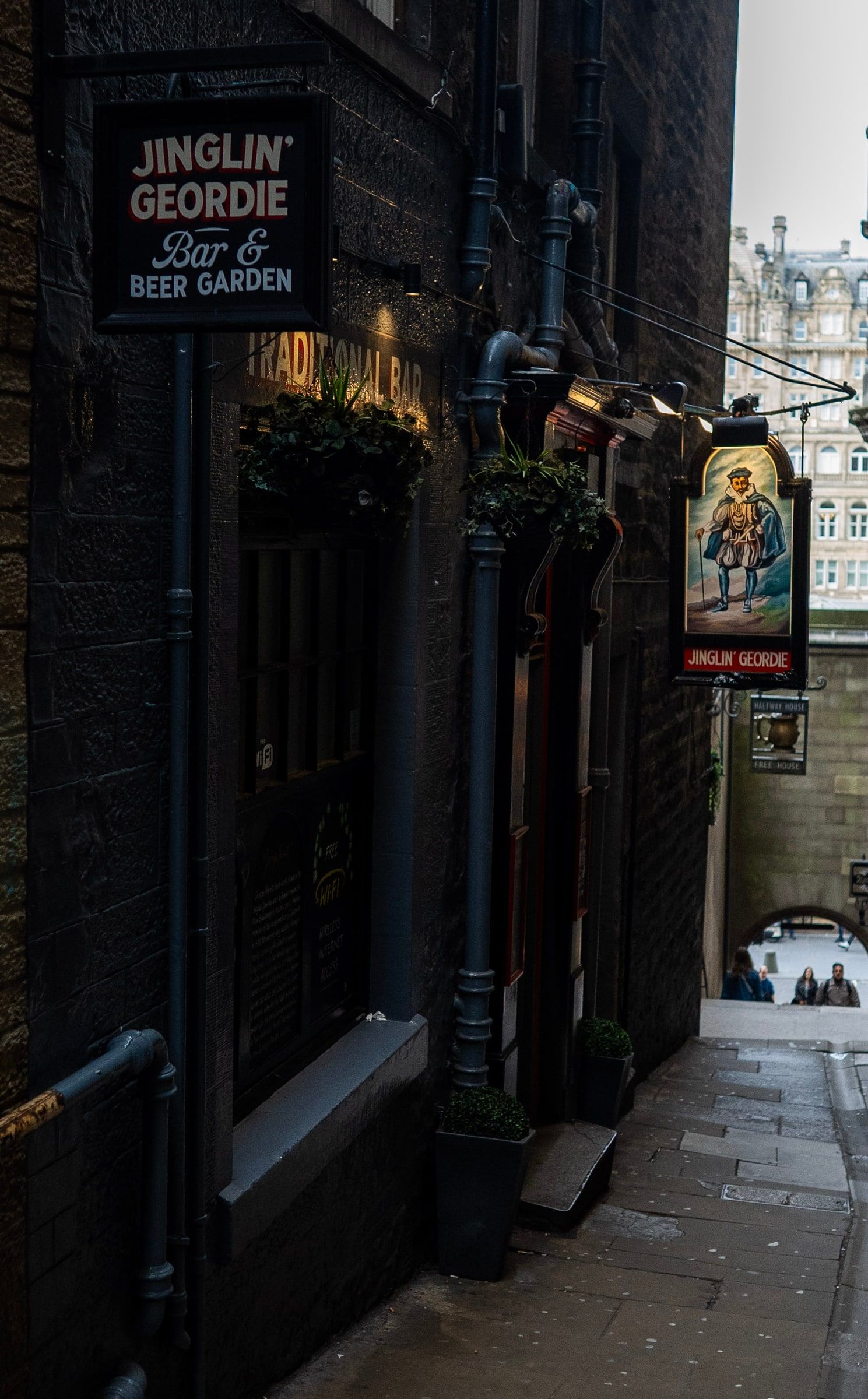 Looking down Fleshmarket Close past the pub signs to the arch onto Market Street